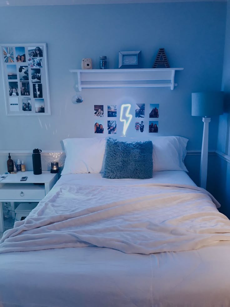 a white bed sitting in a bedroom next to a wall with pictures hanging on it