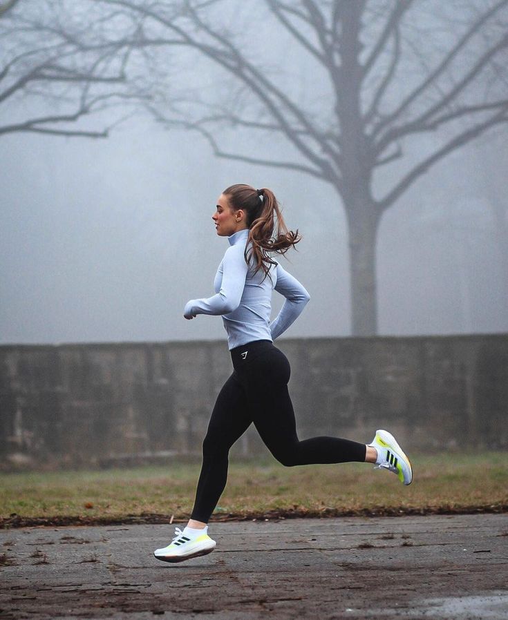 a woman running in the rain on a foggy day