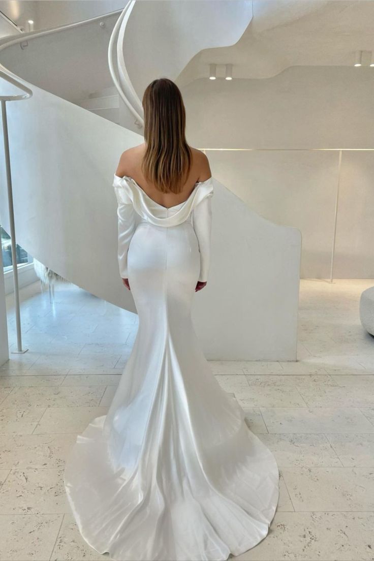 a woman in a white wedding dress looking down at the floor and back of her gown