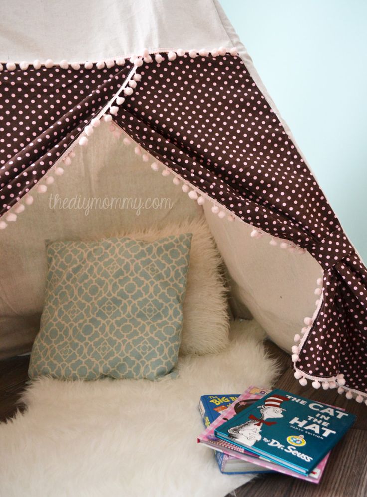 a teepee with some books on the floor and a pillow in front of it