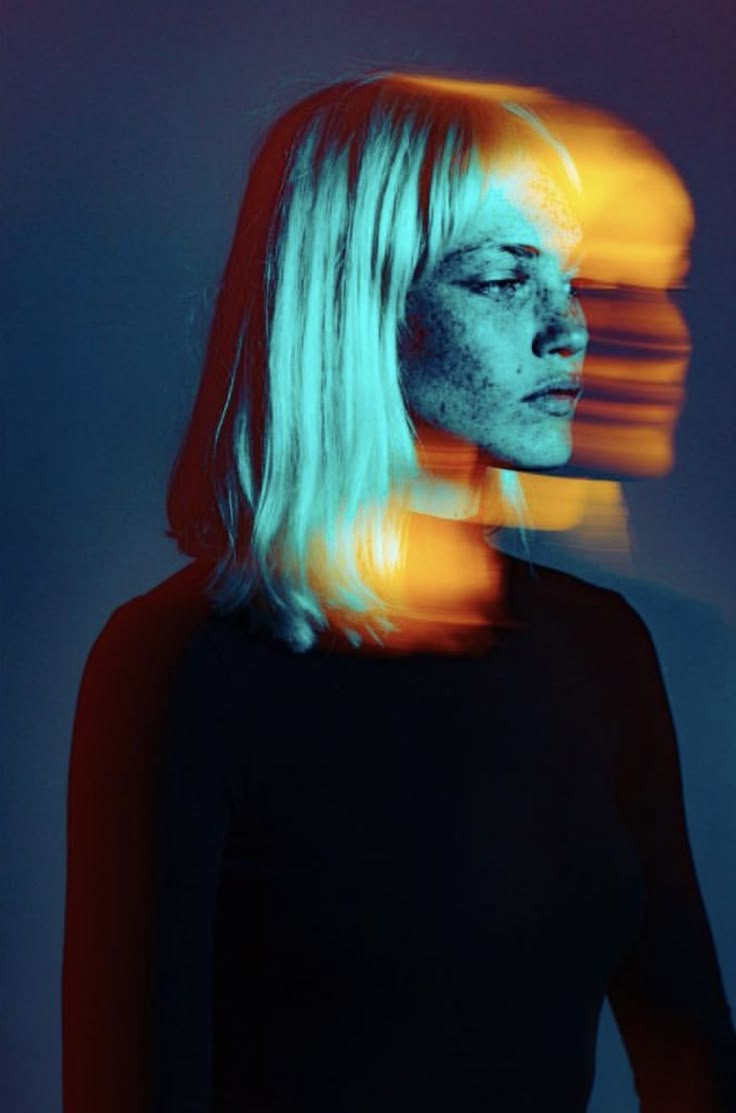 a woman with long blonde hair standing in front of a blue background