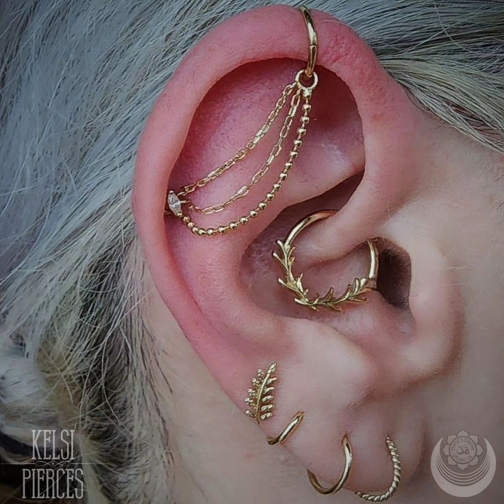 the ear is adorned with gold chains and leaves, as well as an ear cuff