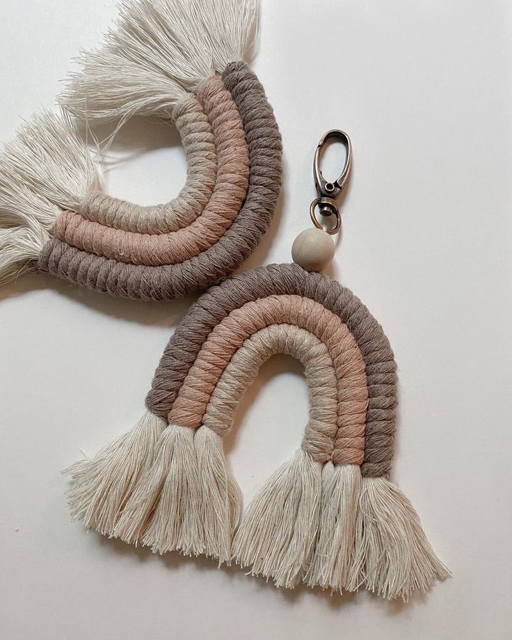 two tasseled earrings on a white surface with a keychain hanging from the end