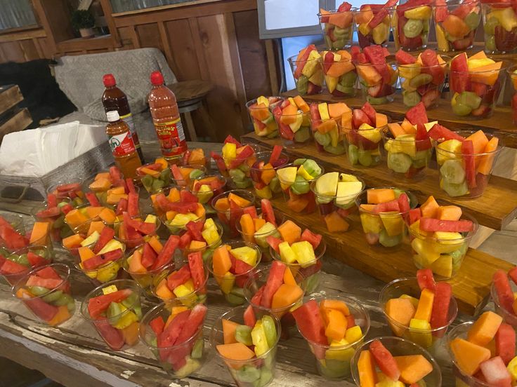 a table topped with lots of cut up fruit on top of glass cups filled with liquid