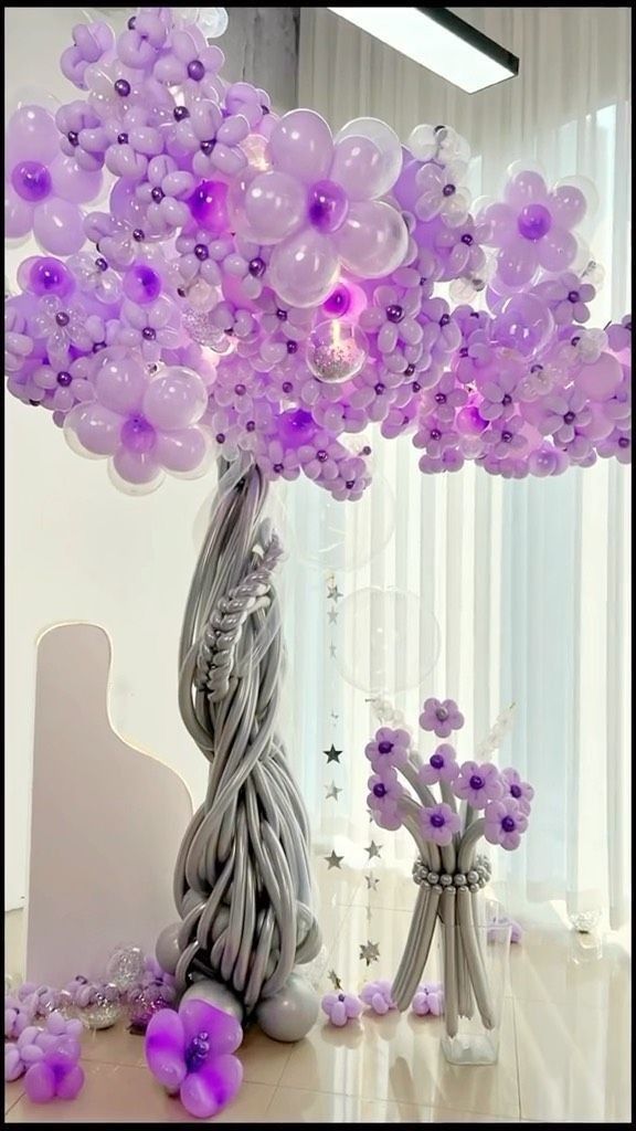 a bunch of balloons are in the shape of a tree with purple flowers on it