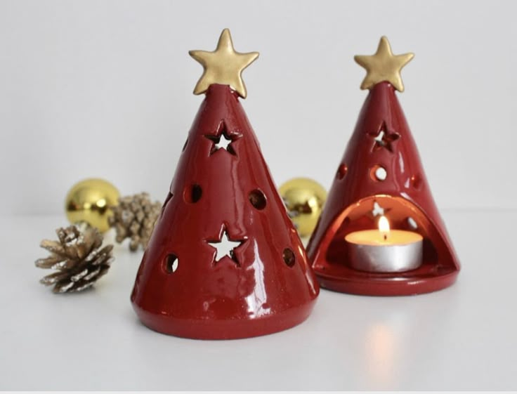 two red christmas trees with gold stars on them and a lit candle in the middle