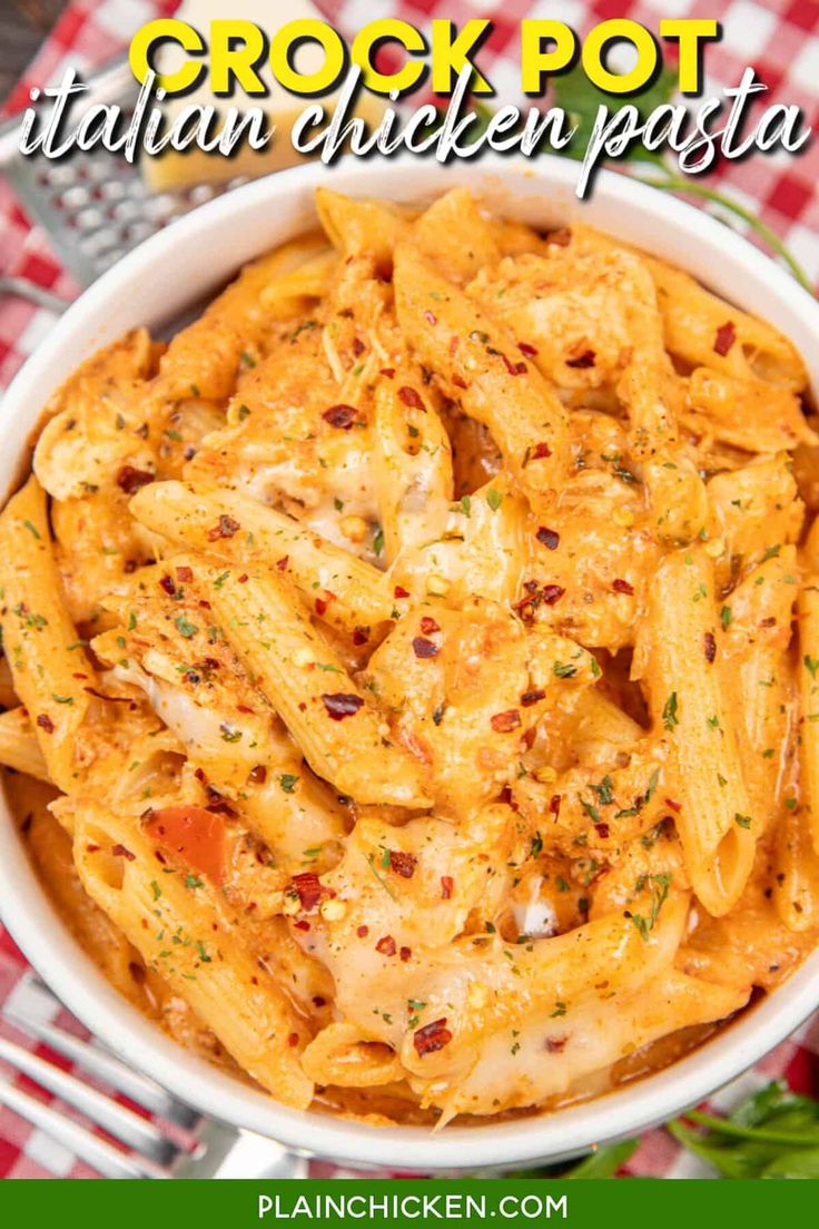 a white bowl filled with chicken pasta on top of a red and white checkered table cloth