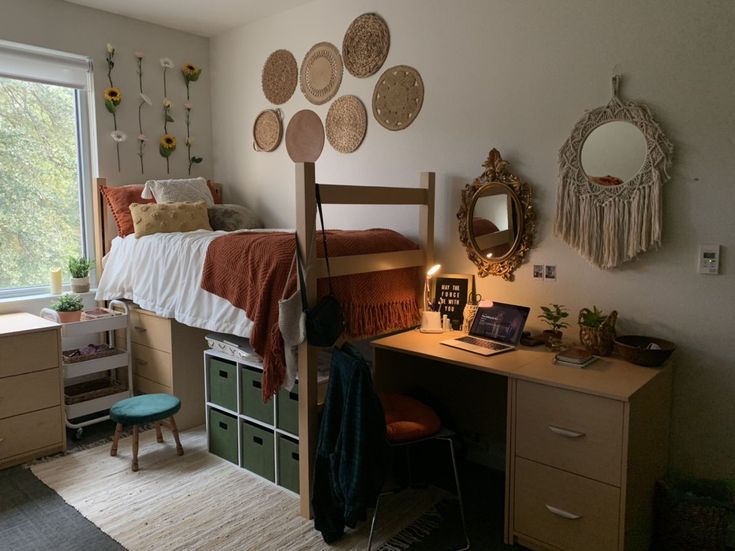 a bedroom with a bed, desk and dresser next to a large window in the corner