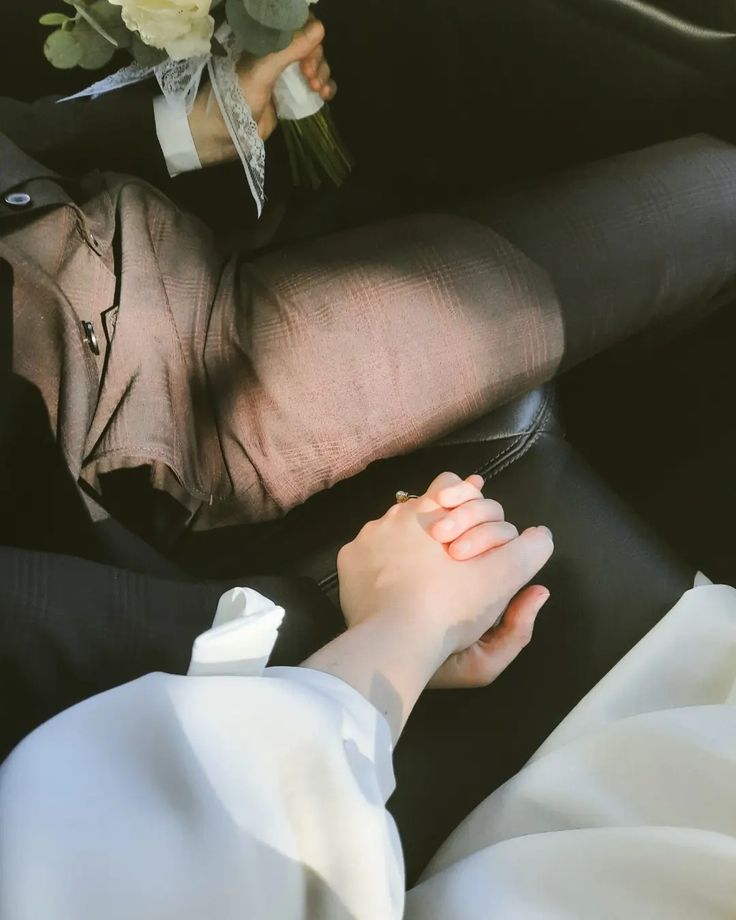 a woman laying on top of a black couch next to a white flower bouquet in her lap