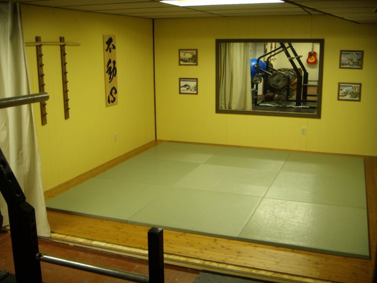 an empty room with yellow walls and green mats on the floor in front of a window