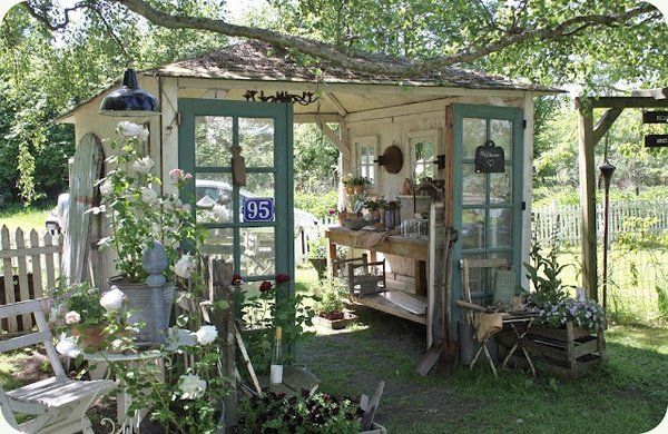 a small shed with lots of potted plants on the front and back porch area