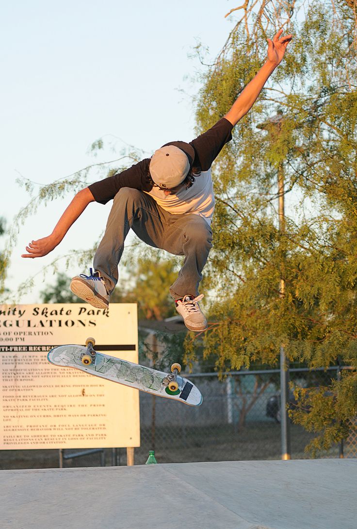 a man flying through the air while riding a skateboard in front of a sign