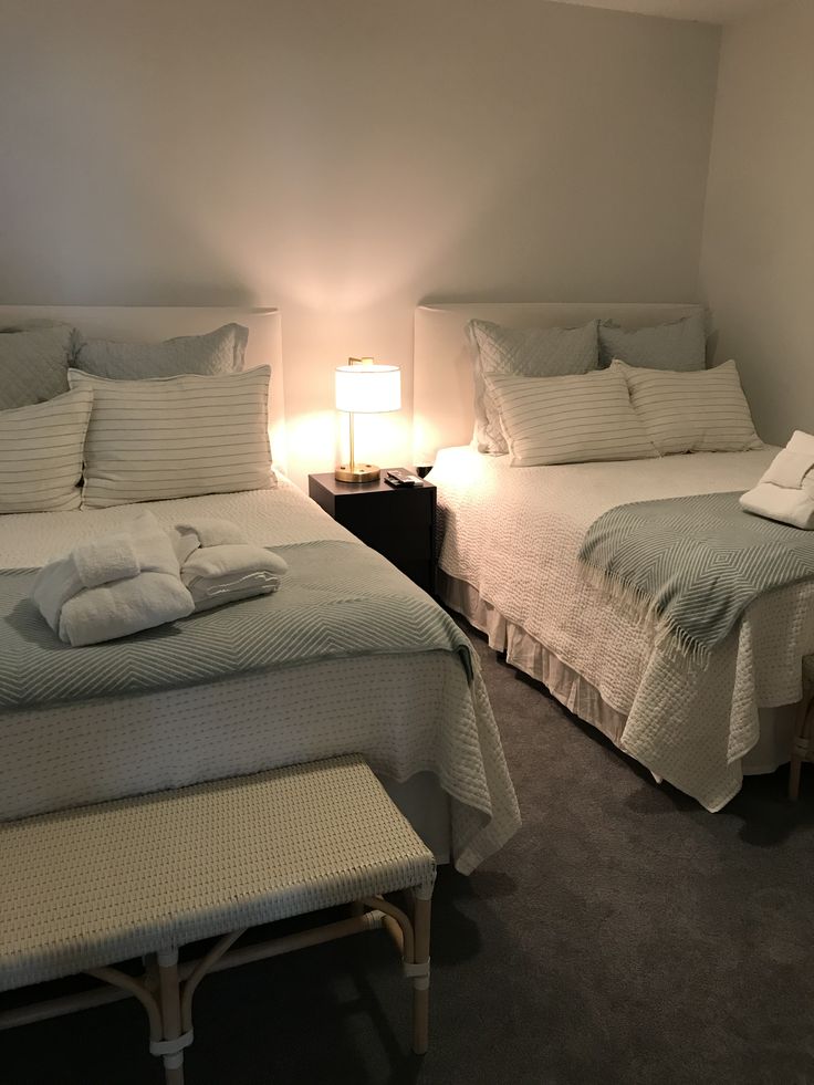 two beds in a bedroom with white sheets and pillows