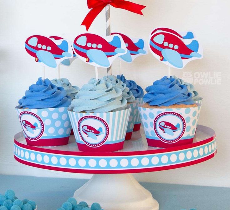 cupcakes with blue frosting and red decorations on a cake platter for an airplane themed birthday party