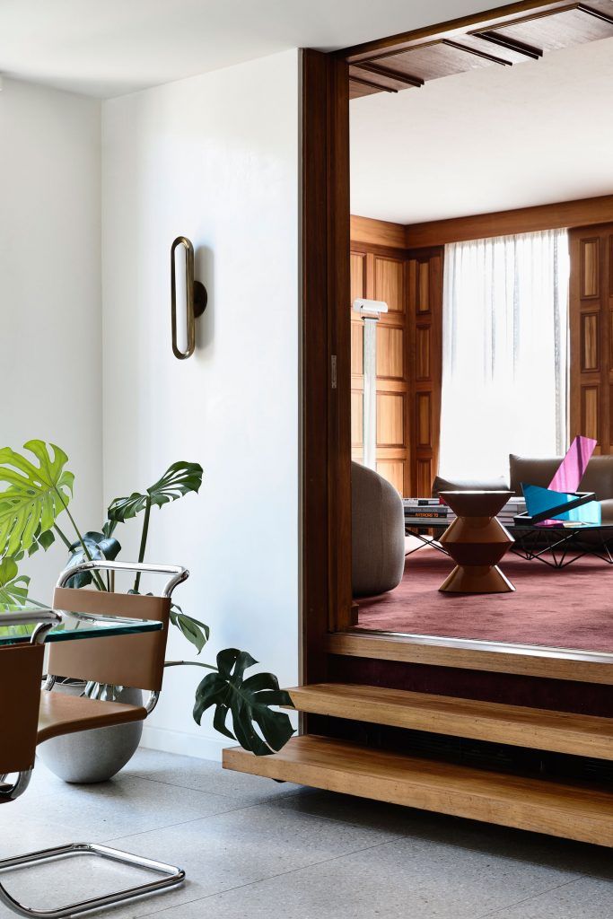 a living room filled with furniture and a large mirror on the wall next to a potted plant