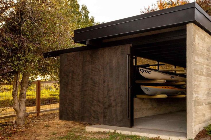 two kayaks are in the storage shed on the side of the road near trees