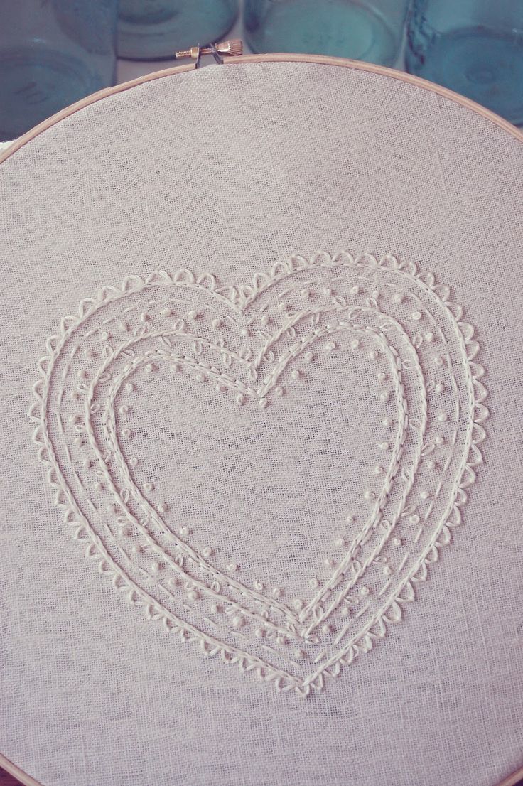 a heart - shaped embroidered on a white piece of cloth with some thread in the middle