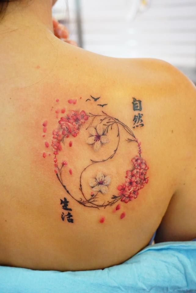 the back of a woman's shoulder with flowers on it and chinese characters in the background