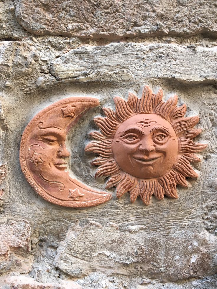 two sun and moon faces on a stone wall