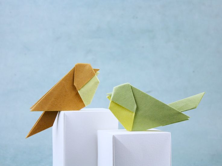 two origami birds sitting on top of white blocks