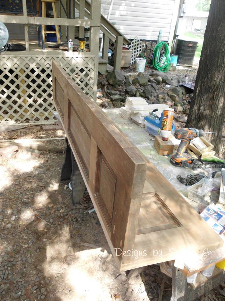 a wooden bench sitting in the middle of a yard next to a tree and fence