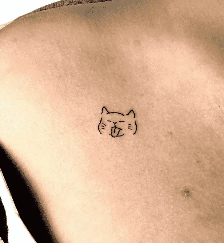 a small cat tattoo on the back of a woman's left side ribcage