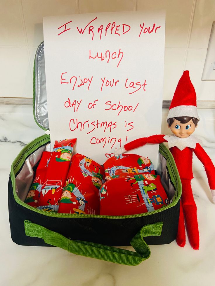 an elf is holding a sign and some presents in a suitcase with the message i wrapped your lunch enjoy your last day of school christmas coming