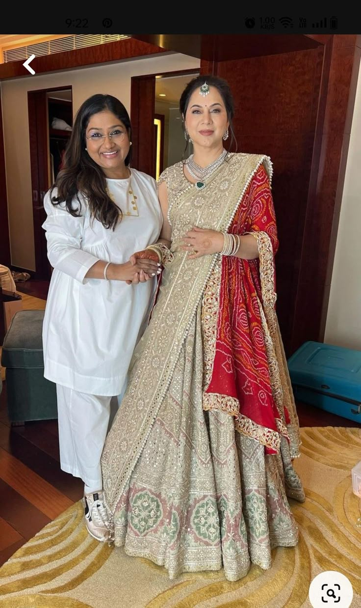 two women standing next to each other in white outfits