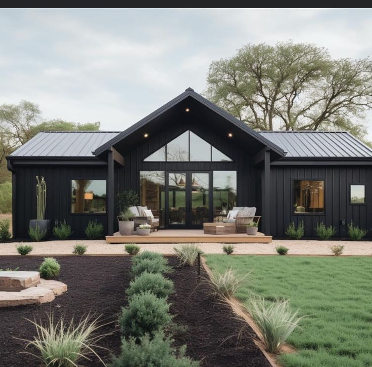 a black house with lots of windows and grass