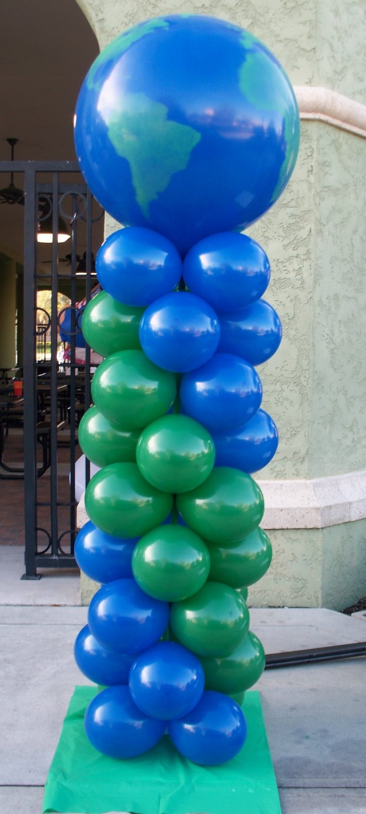 blue and green balloons are stacked on top of each other in front of a building