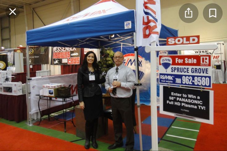 two people standing in front of a tent at an event with signs on the ground