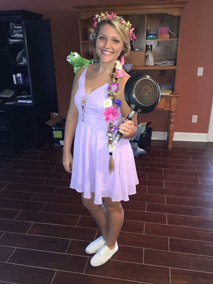 a woman in a pink dress holding a black pan and flower garland on her head