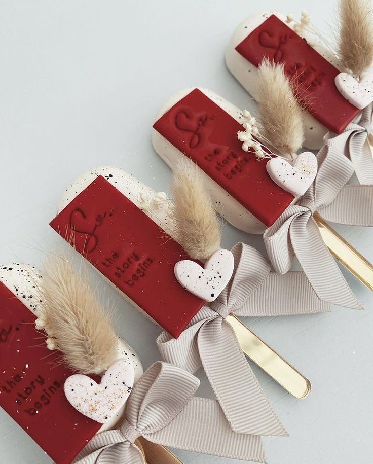 three red and white toothbrushes decorated with feathers, bows and hearts on them