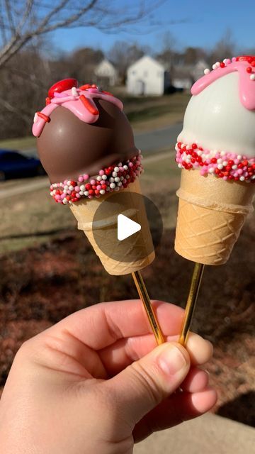 two ice cream cones with sprinkles on them being held by someone's hand