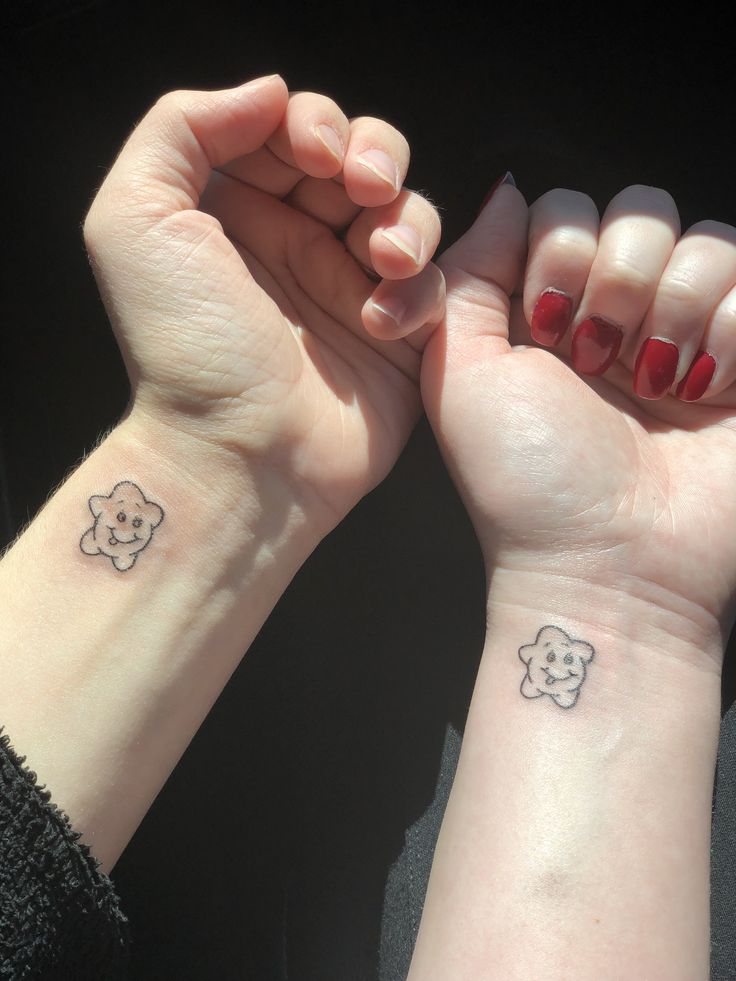 two people with matching tattoos on their wrist holding each other's hands in the air