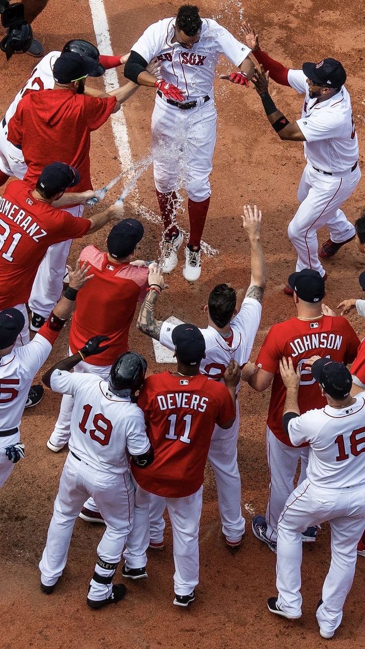 a group of baseball players standing next to each other on top of a dirt field