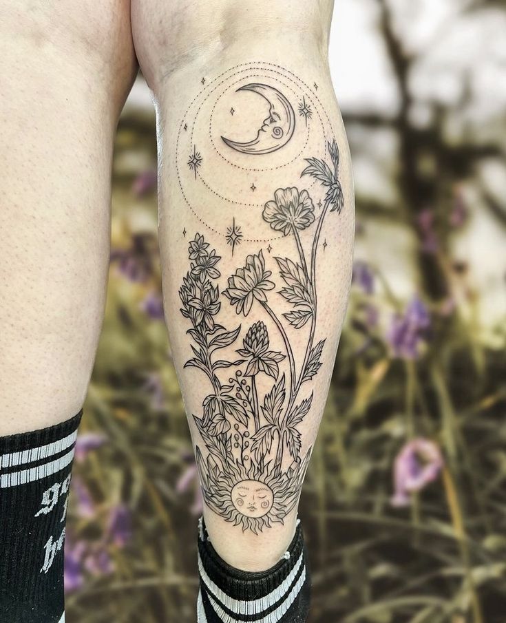 a man's legs with flowers and a moon tattoo on the lower half of his leg