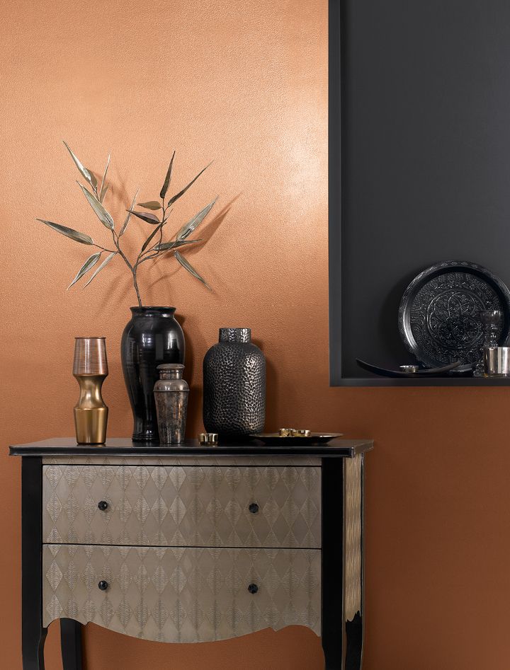 a table with vases and plates on it next to a wall that has gold paint