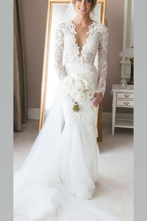 a woman in a wedding dress is standing next to a mirror and holding a bouquet