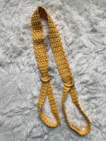 two yellow crocheted straps laying on top of a white rug