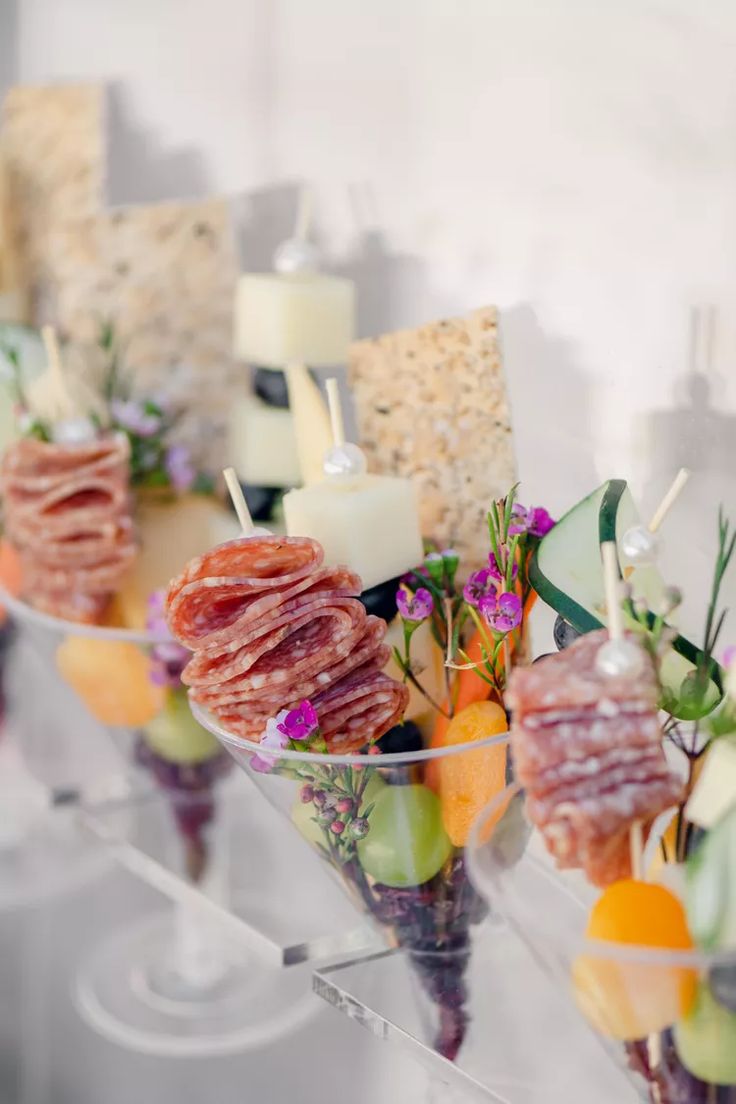 a table topped with lots of different types of food on top of glass cups filled with candles