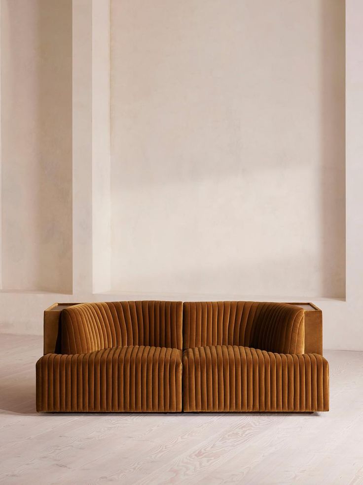 a brown couch sitting on top of a white floor next to a wall in an empty room