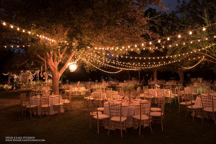 an outdoor event with tables and chairs set up for dinner under the trees at night