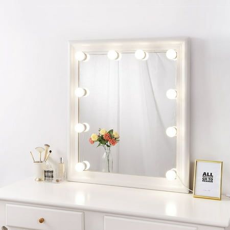 a white dresser topped with a mirror and lights