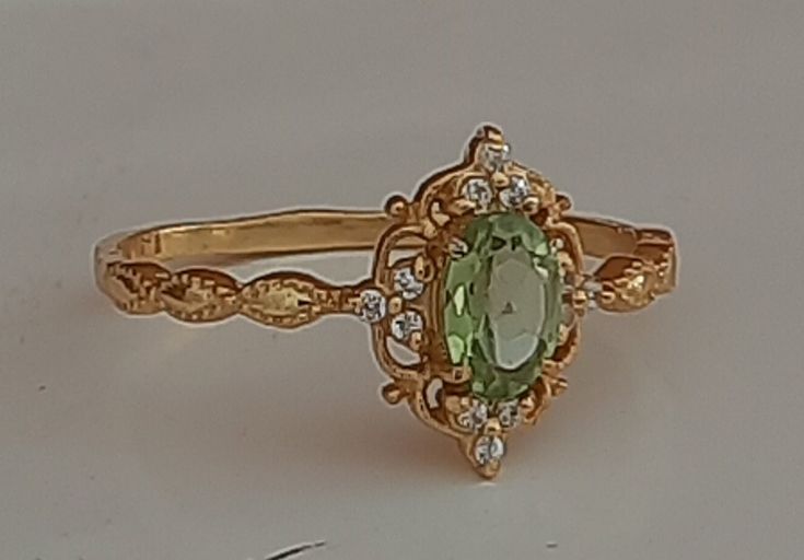 an oval shaped green ring with diamonds on the sides and in the middle, sitting on a white surface