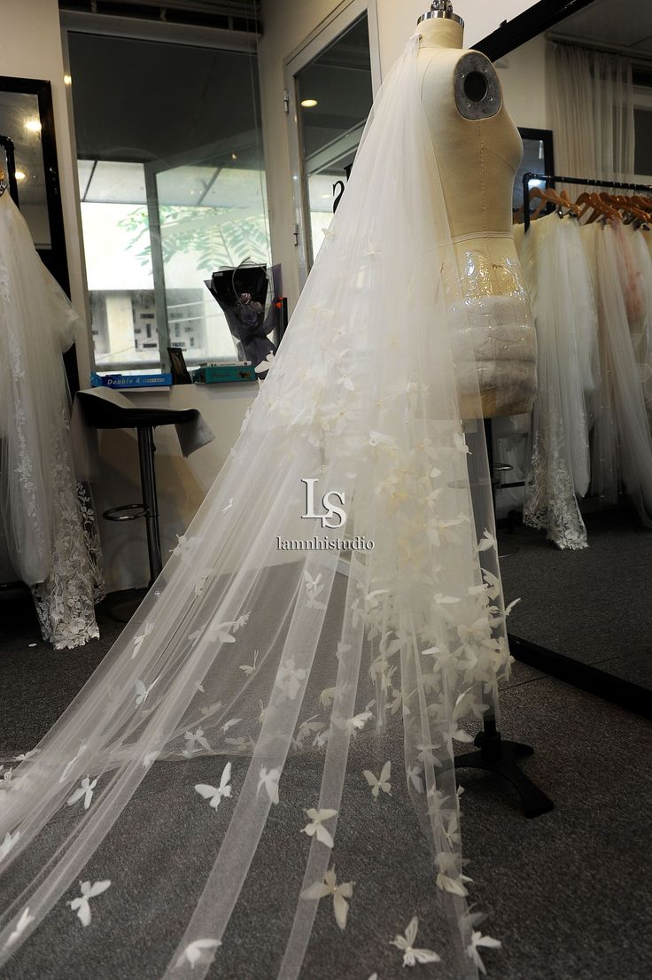 a wedding dress on display in a bridal room with veils and butterflies all over it