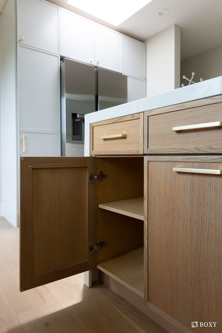 an open cabinet door in a kitchen next to a sink and counter top with drawers