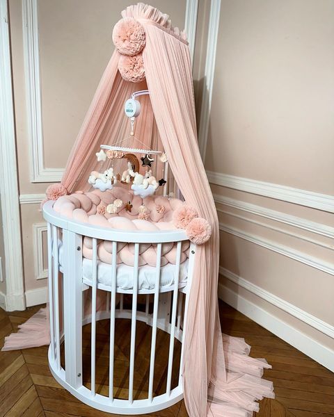 a baby crib with pink and white decor