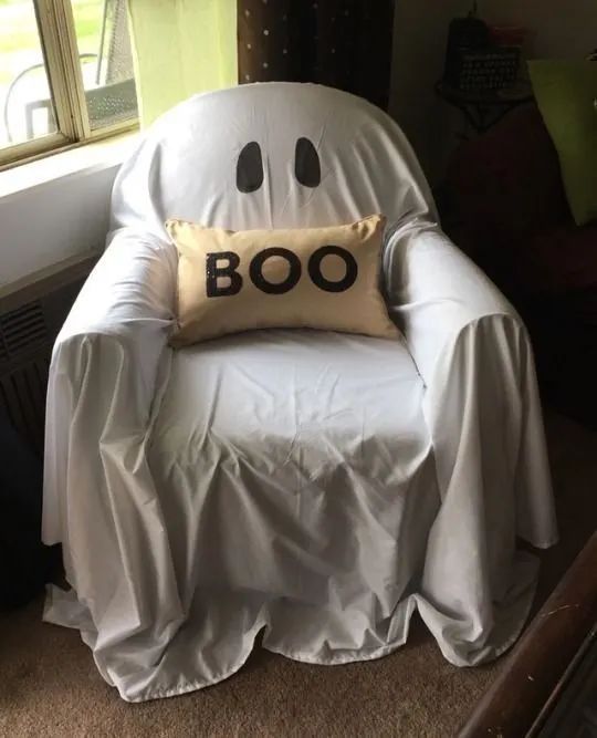 a ghost chair with a boo pillow on it's back in front of a window