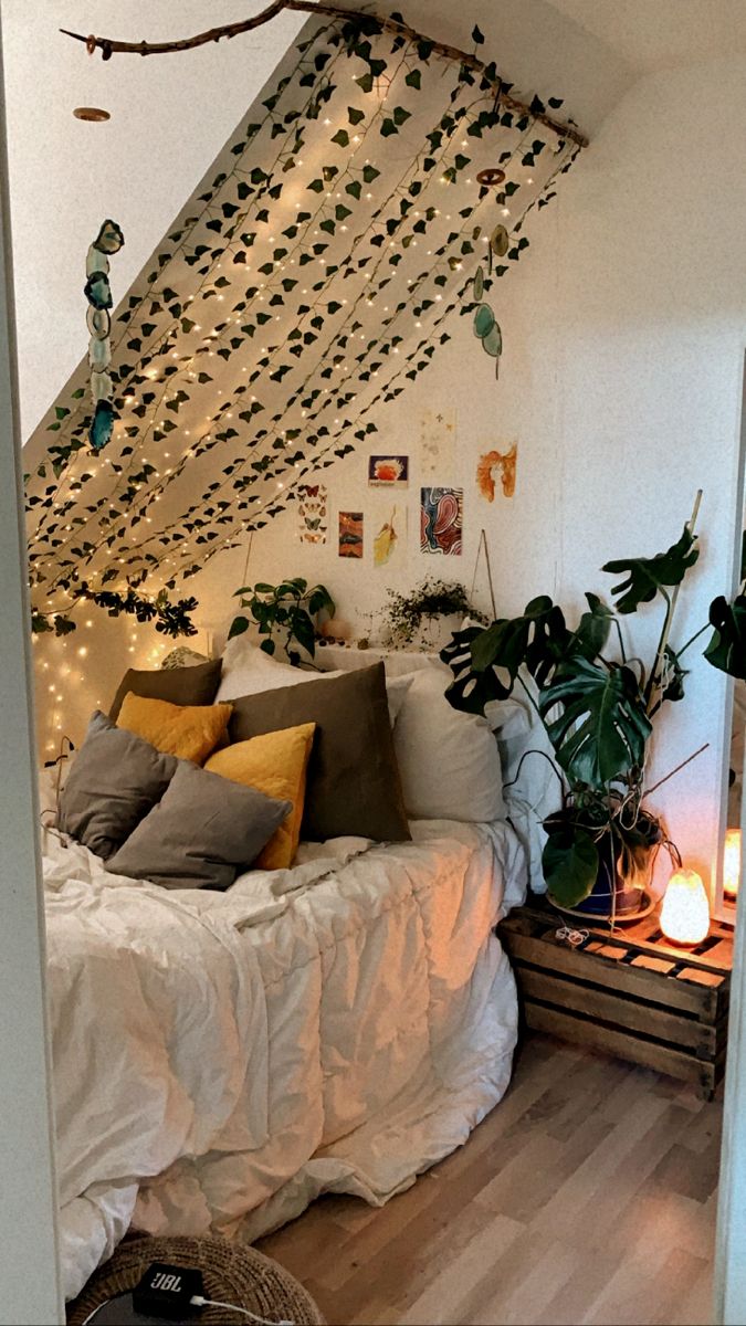 a bed with lots of pillows on top of it next to a wall covered in lights